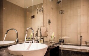 Une salle de bain moderne avec deux lavabos, une baignoire et une douche séparée par une paroi en verre.