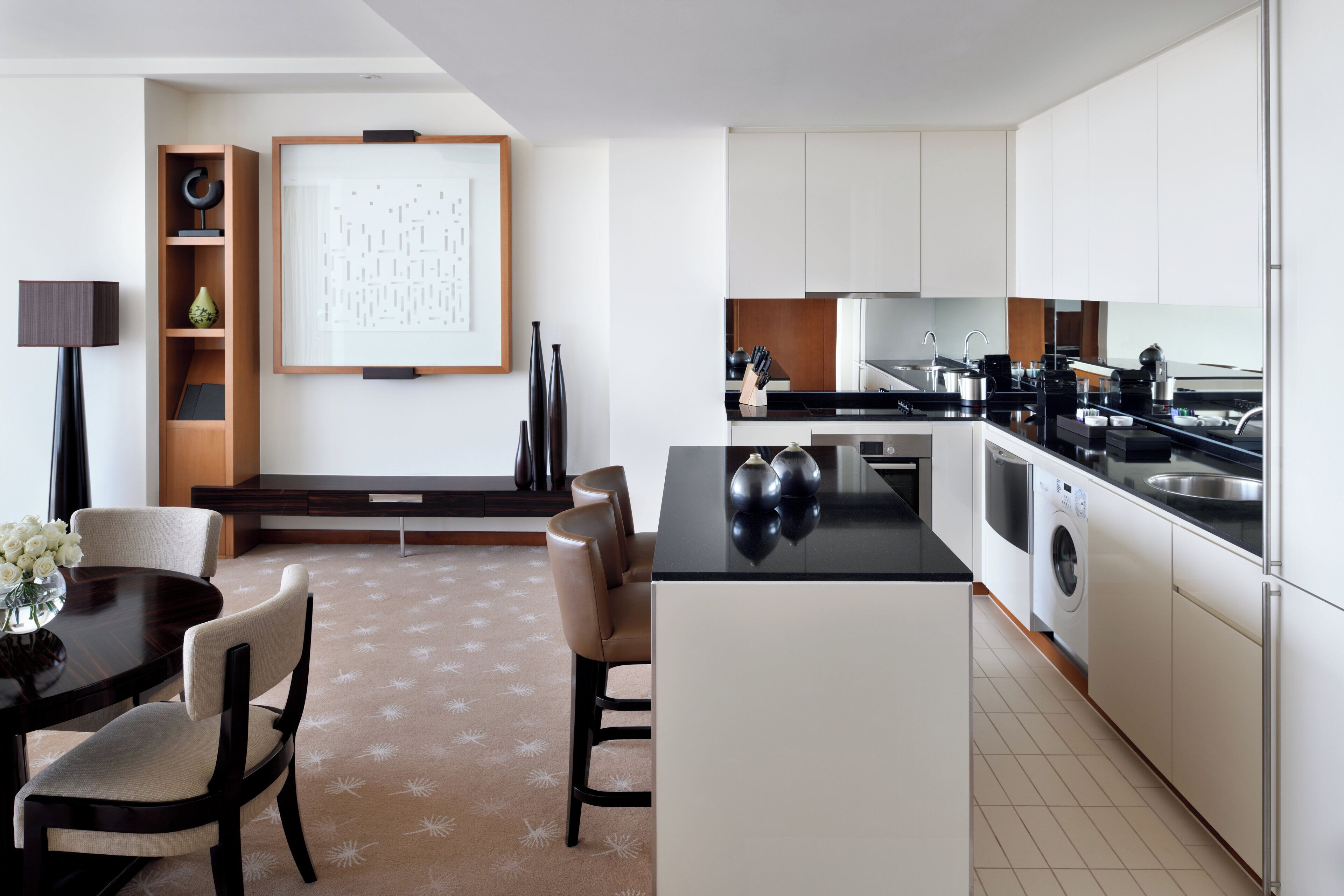 A modern kitchen with white cabinets, a black countertop, and a built-in washing machine.
