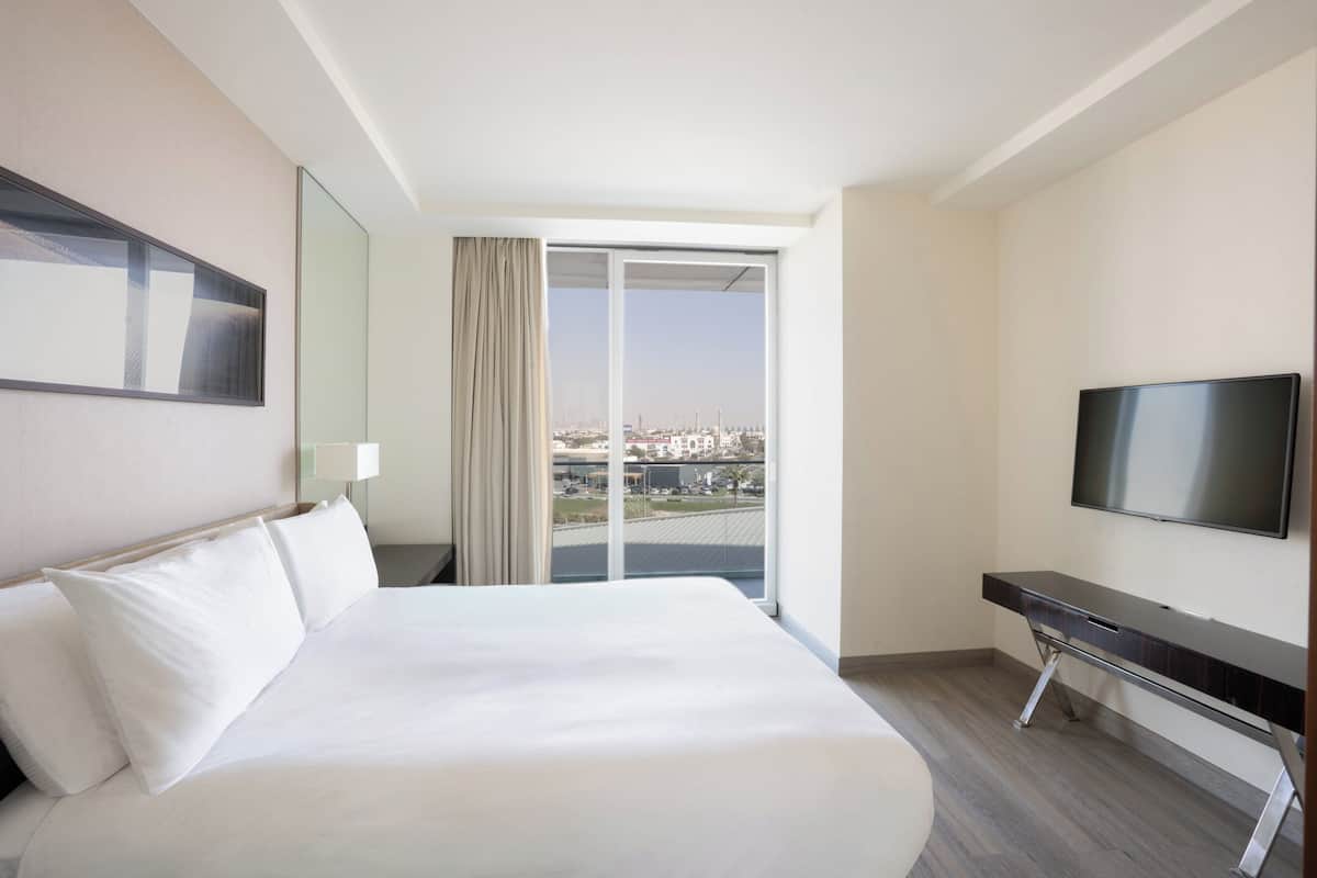 Une chambre d’hôtel avec un grand lit, une télévision, un bureau et une vue sur la ville par la fenêtre.