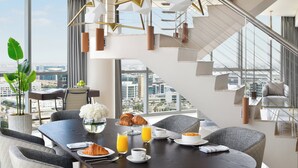 A modern dining area with a city view, a staircase, and a dining table set with breakfast items. - InterContinental Residence Suites Dubai Festival City by IHG (Dubai)