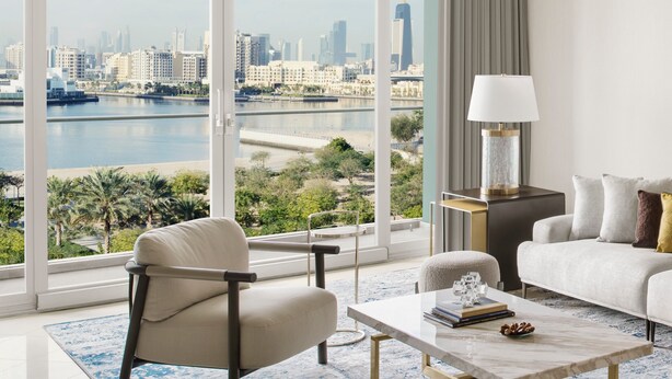 A modern living room with a large window offering a city view, a sofa, a chair, a coffee table, and a lamp. - InterContinental Residence Suites Dubai Festival City by IHG (Dubai)