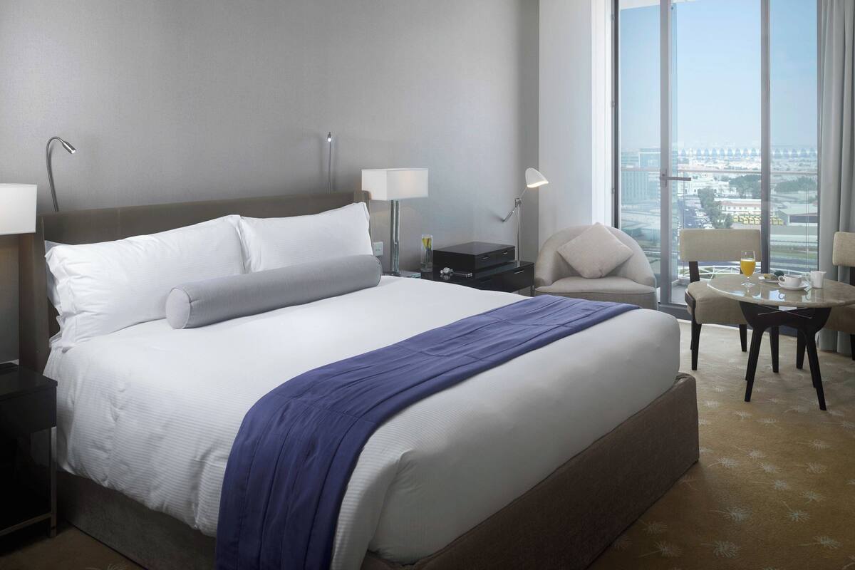 Une chambre d’hôtel avec un grand lit, un bureau avec une chaise, une télévision et une vue sur la ville.