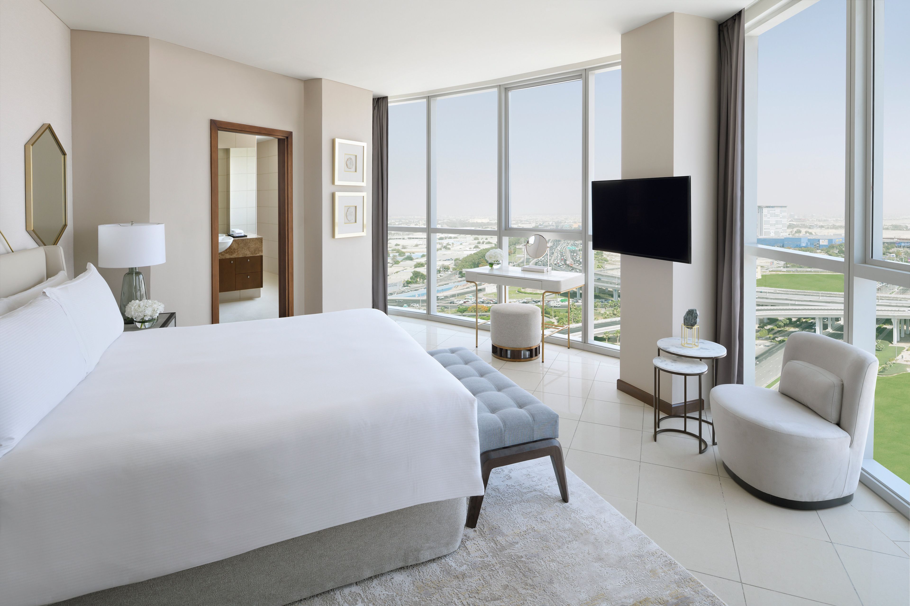Une chambre d’hôtel moderne dotée d’un grand lit, d’un coin salon, d’une télévision et offrant une vue sur la ville.