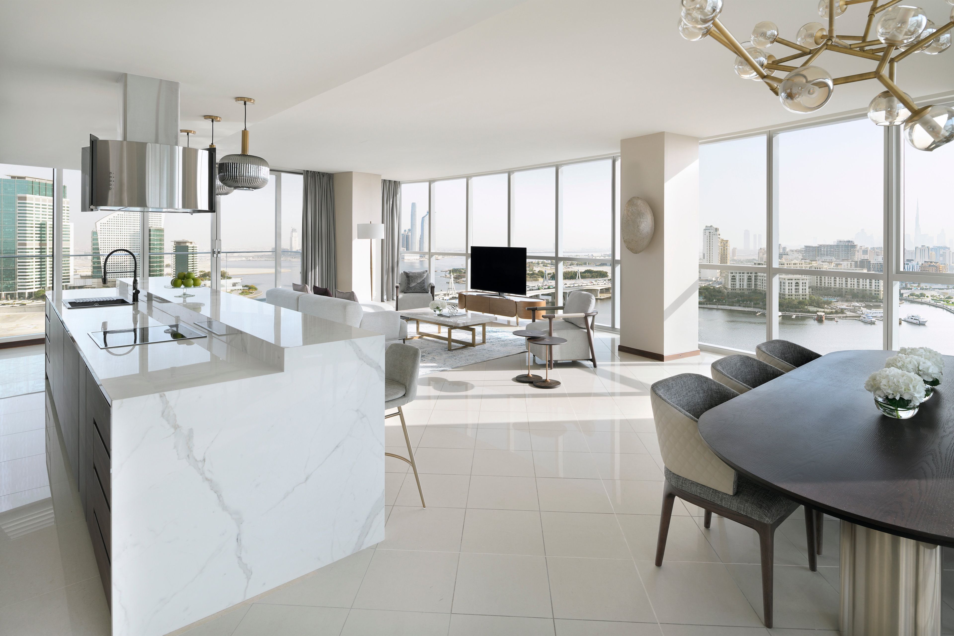 Eine moderne Küche mit Marmorarbeitsplatte, einem Essbereich mit rundem Tisch und einem großen Fenster mit Blick auf die Stadt.