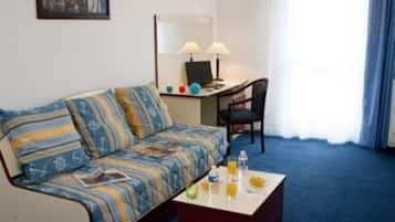 Et hotelværelse med sofa, skrivebord med computer, stol og sofabord.