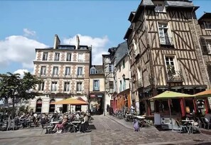 A cobblestone street with traditional European architecture, outdoor seating for cafes, and bicycles parked along the sidewalk. - Appart'City Classic Rennes Beauregard (Rennes)