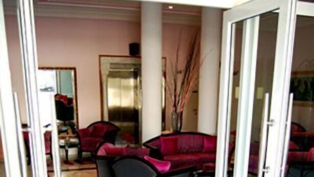 A hotel lobby with a red sofa, a glass door entrance, and a marble floor with a circular design.
