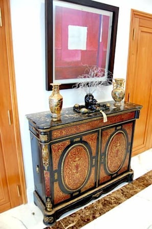 Un mueble oscuro y decorativo con dos jarrones y una obra enmarcada encima.