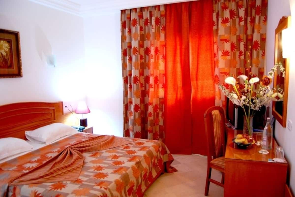 Ein Hotelzimmer mit Bett, Schreibtisch und Blumenvase sowie einem Stuhl.