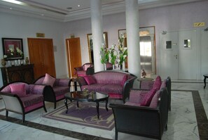 Un vestíbulo amplio con una zona de estar que incluye sofás y sillones, una mesa de centro y un suelo de mármol.