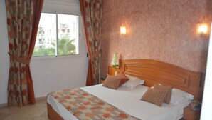 A neatly made bed with a floral bedspread, a wooden headboard, and two wall-mounted lights.
