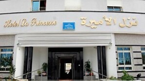 A hotel entrance with a modern facade, a name sign, and a blue signboard.