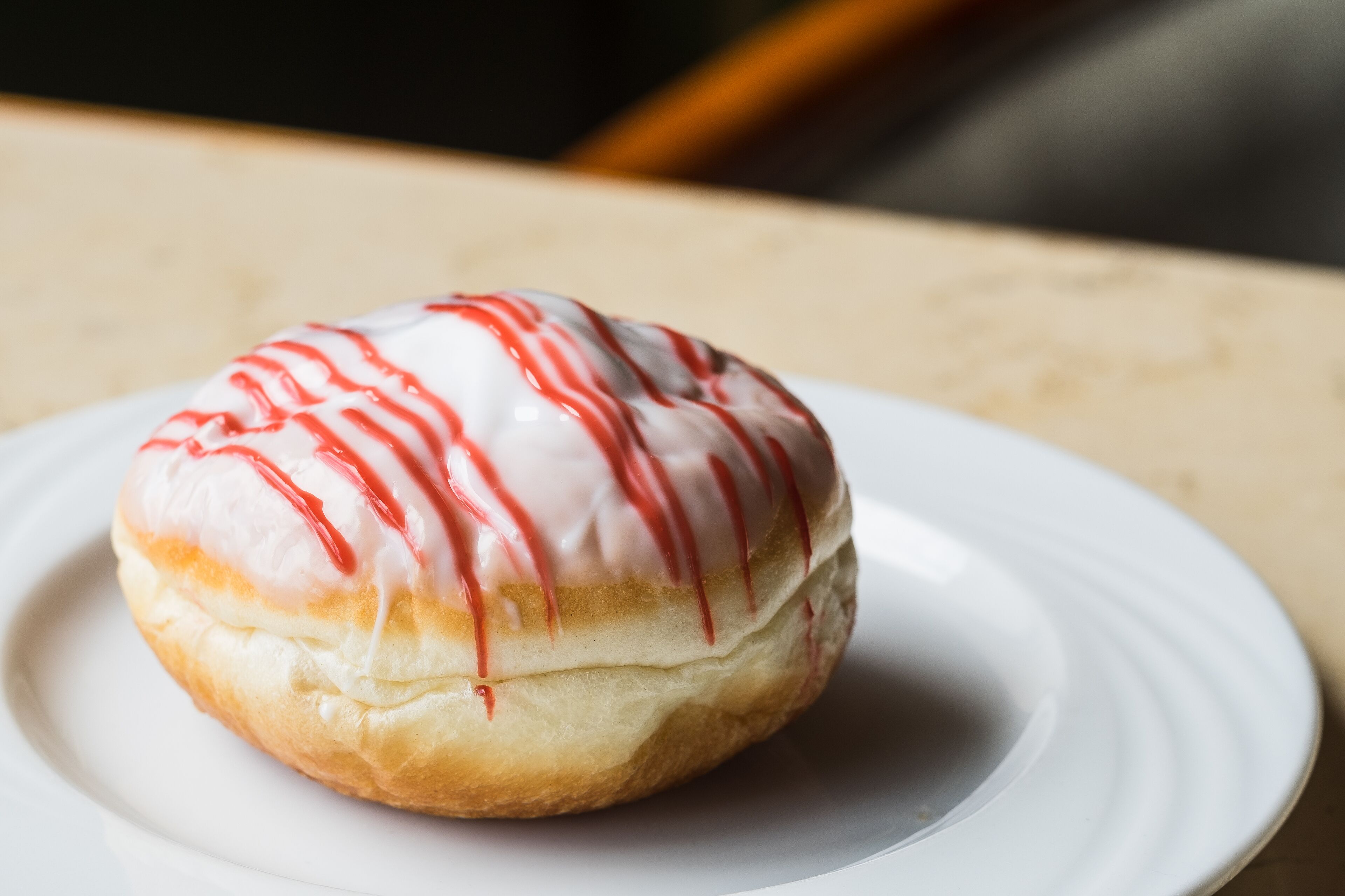A white plate with a single glazed donut on a table.