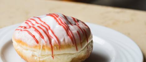 A white plate with a single glazed donut on a table.
