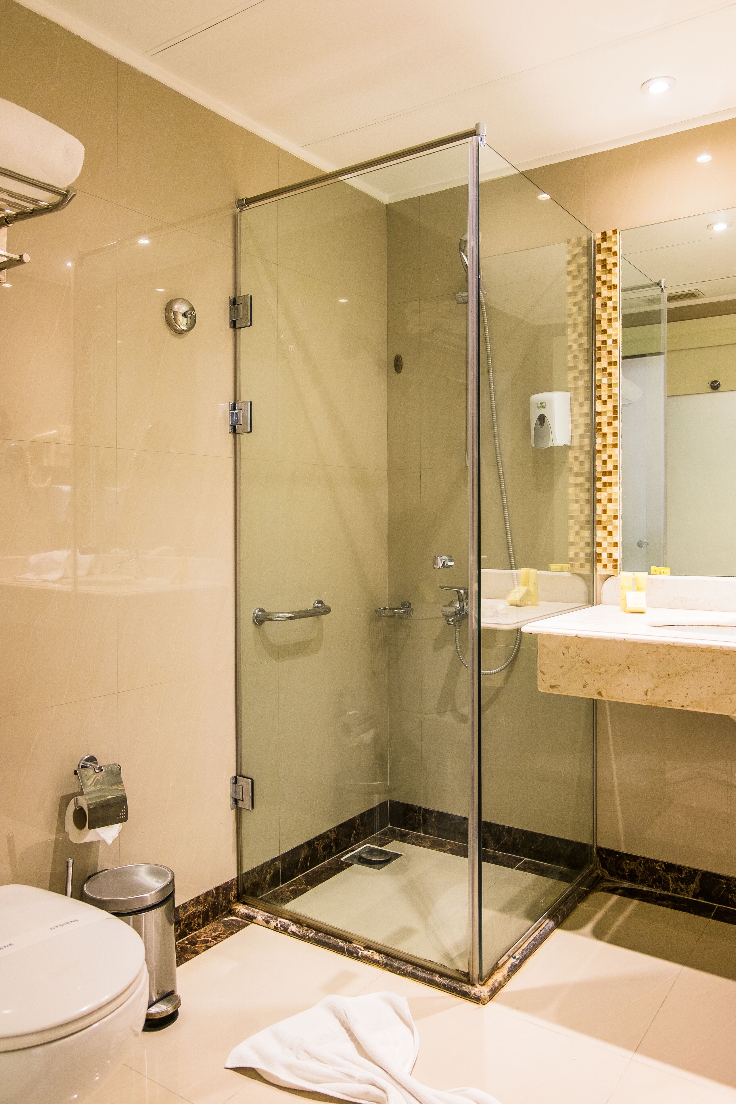 Un bagno moderno con doccia vetro, un water e un lavandino con specchio sopra.