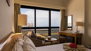 Une chambre d’hôtel avec une grande fenêtre, un lit, un bureau et une chaise.