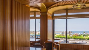 Un espace de restauration moderne avec un lambris en bois, un lustre et une vue sur la plage.