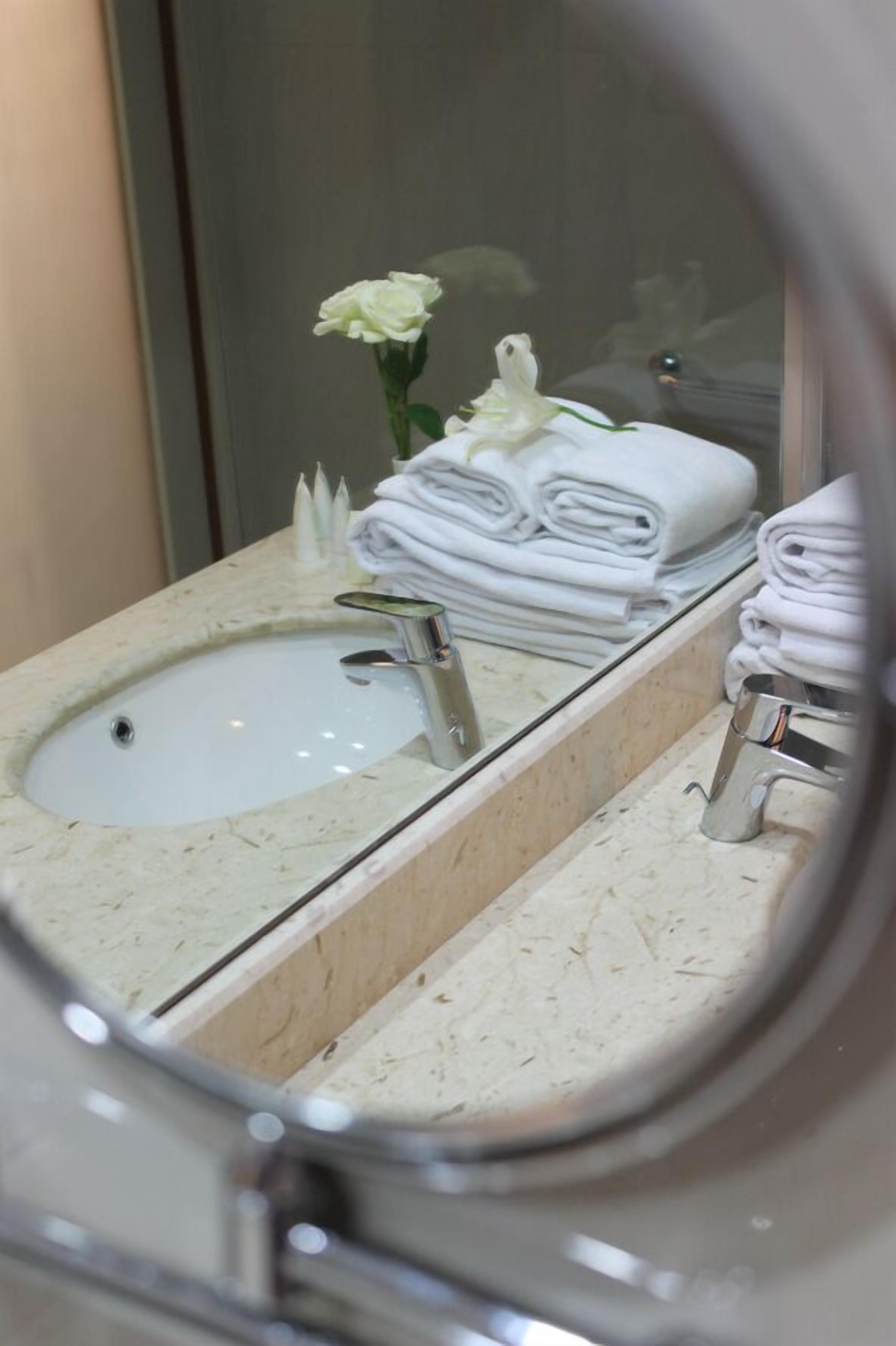 A bathroom with a sink, mirror, and towels.