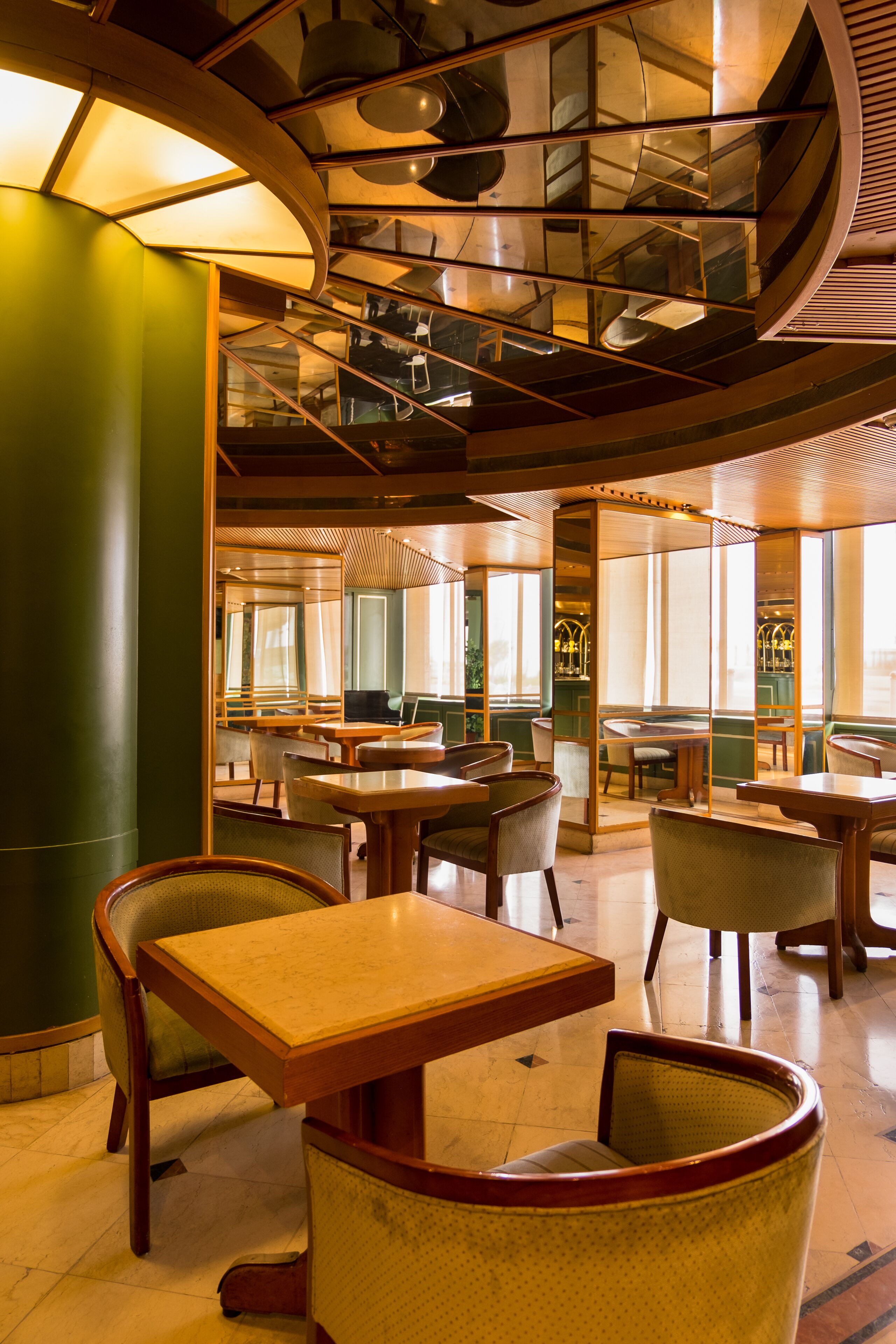 A spacious restaurant with high ceilings, large windows, and modern furniture.