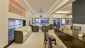 A modern hotel lobby with a reception desk, seating area, and large windows offering city views. - Hotel Airlink (Mumbai)