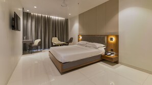 A modern bedroom with a large bed, bedside table, and a desk with a chair. - Hotel Airlink (Mumbai)