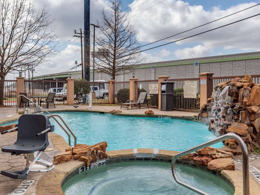 A swimming pool with a hot tub, lounge chairs, and a waterfall feature.