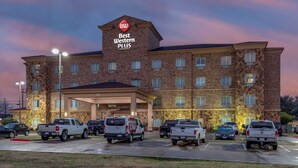 Een Best Western Plus hotel met een gevel van baksteen, diverse parkeerplaatsen en een goed verlichte ingang.