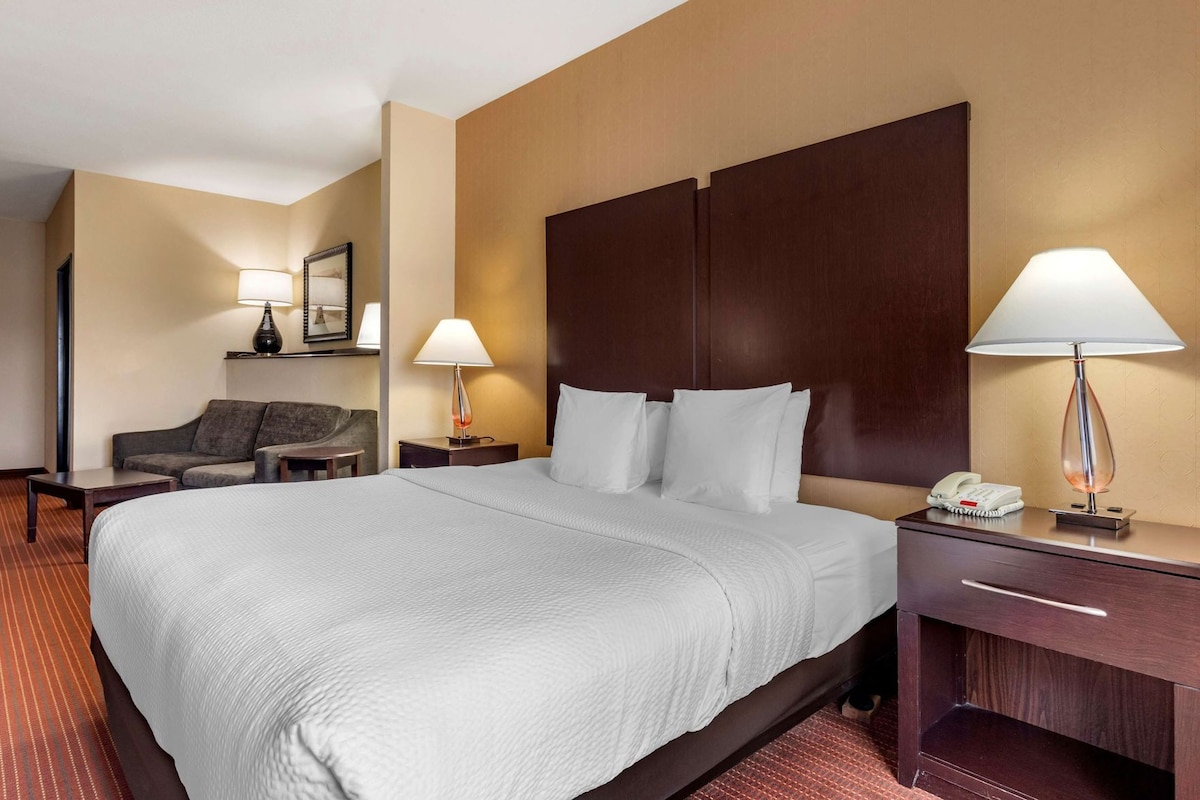 A hotel room with a large bed, two bedside tables, a sofa, and a lamp.
