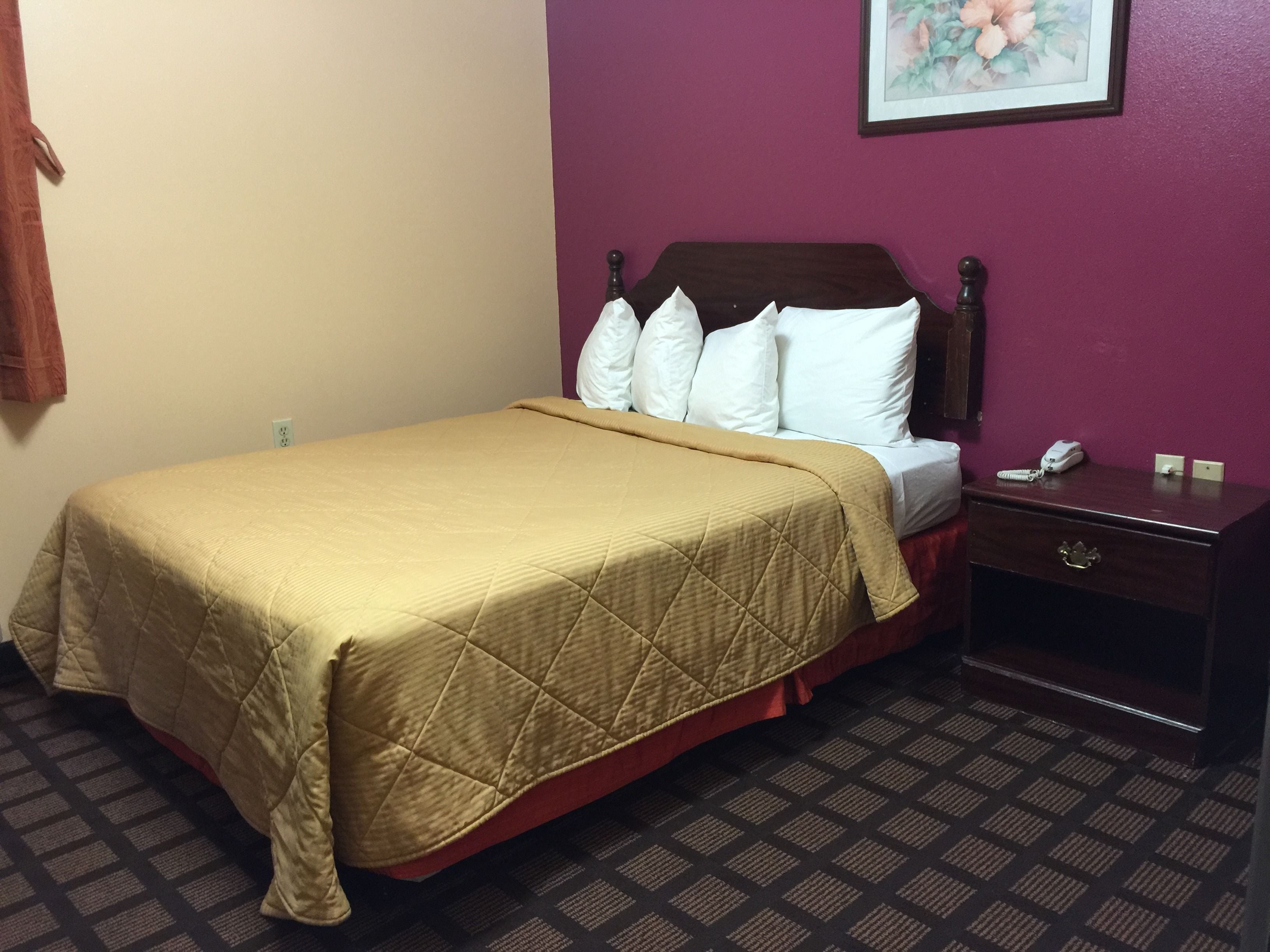 Une chambre d’hôtel avec un lit, une table de chevet et un téléphone.