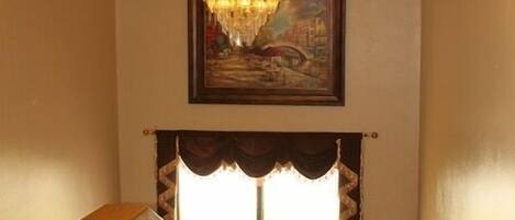 A staircase with a patterned carpet, a chandelier, and a framed painting above.