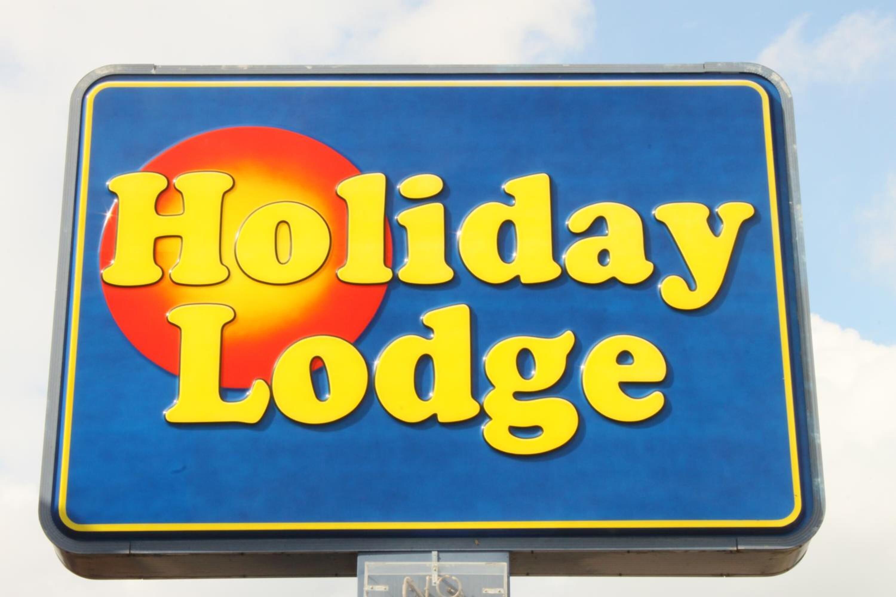 A sign with the text "Holiday Lodge" in yellow letters on a blue background with a red circle.