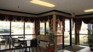 A restaurant interior with a dining area, large windows, and decorative curtains. - Holiday Lodge (Pittsburg)