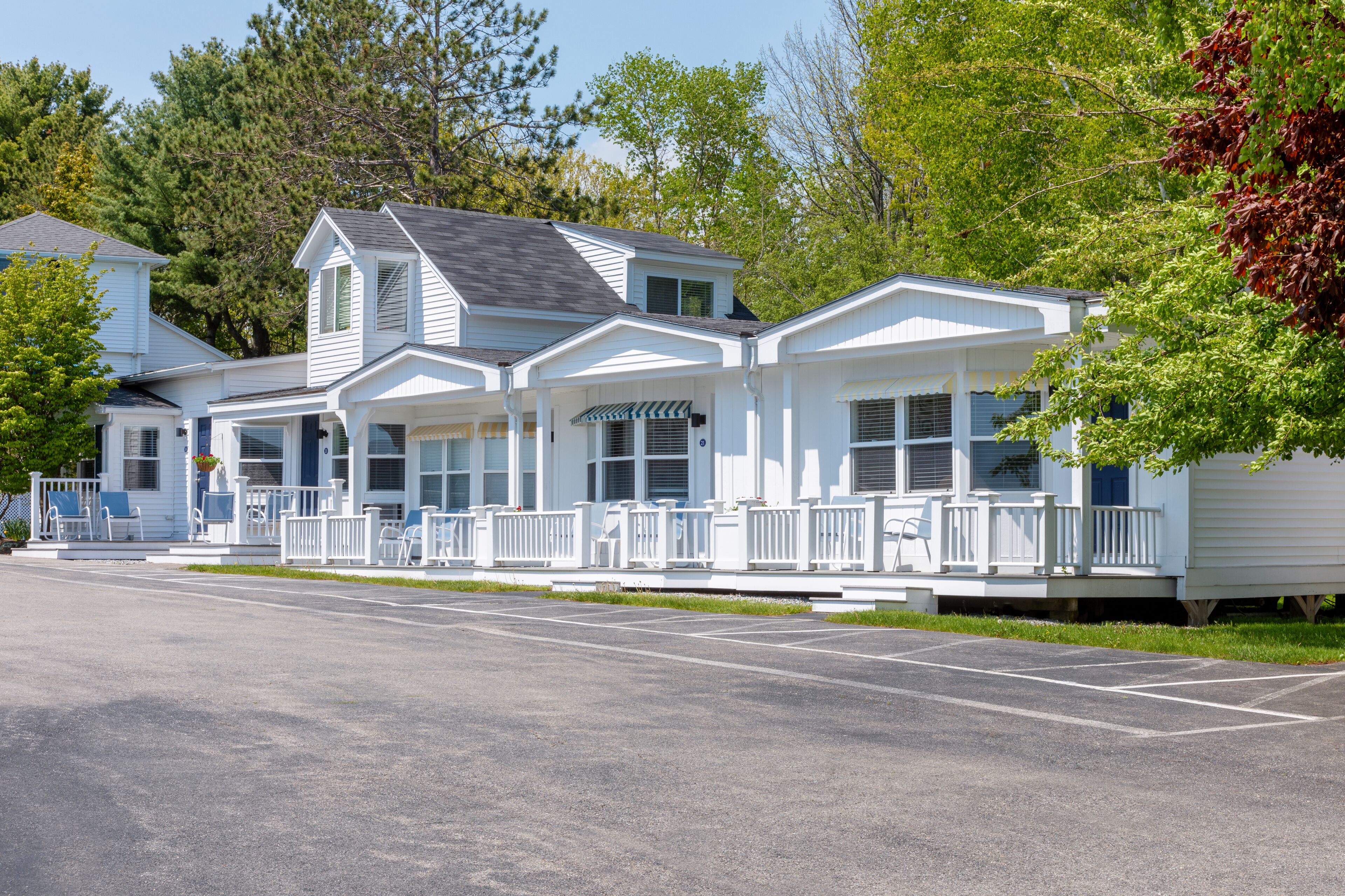 A row of white, single-story houses with attached porches and a covered front porch.