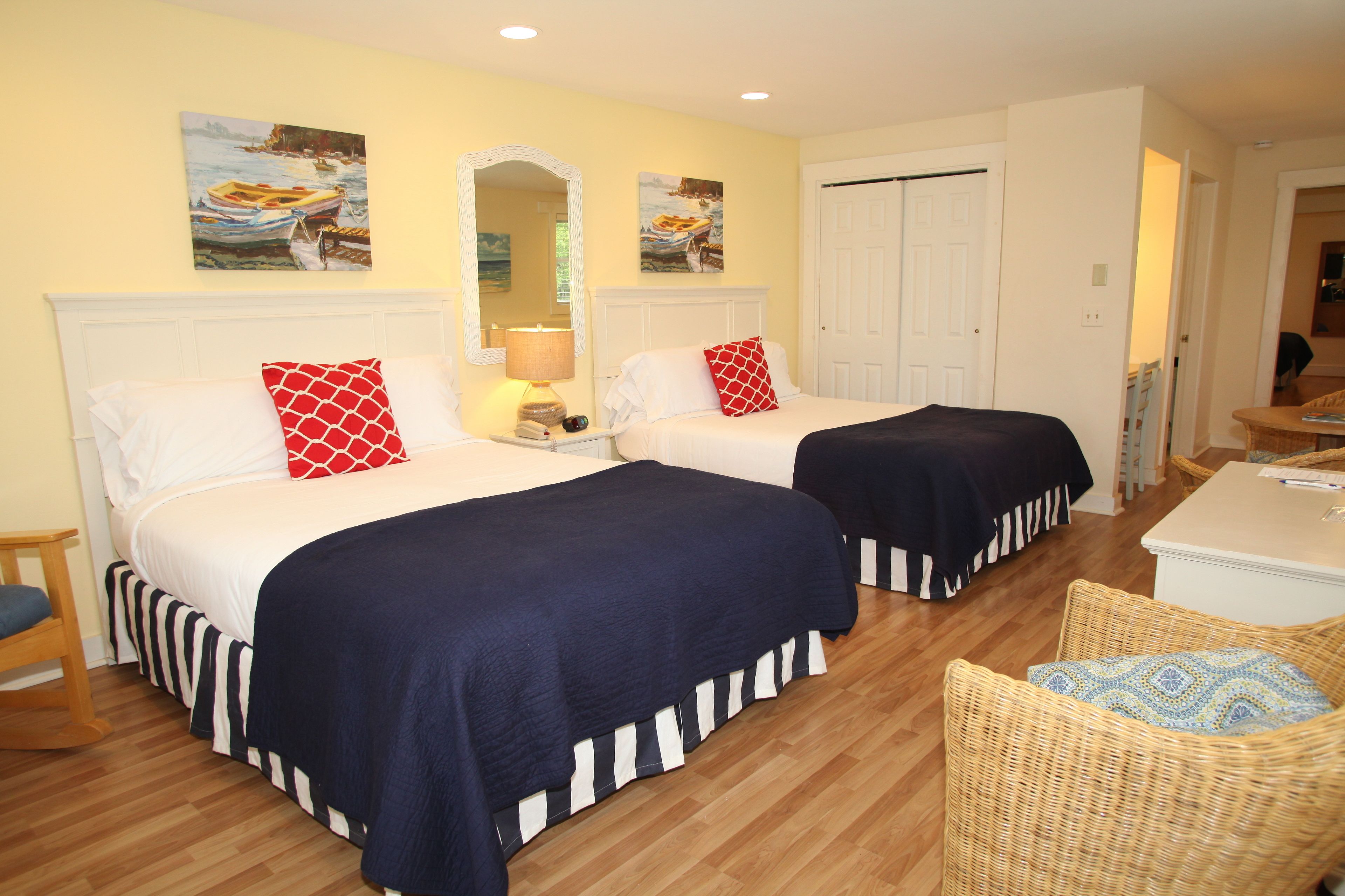 A hotel room with two beds, a wooden floor, a chair, and artwork on the walls.