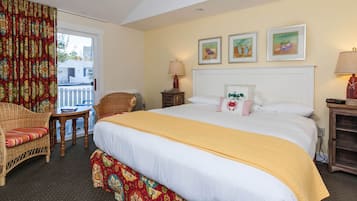 Una habitación de hotel con una cama grande, una silla, una mesita pequeña y una mesita de noche.