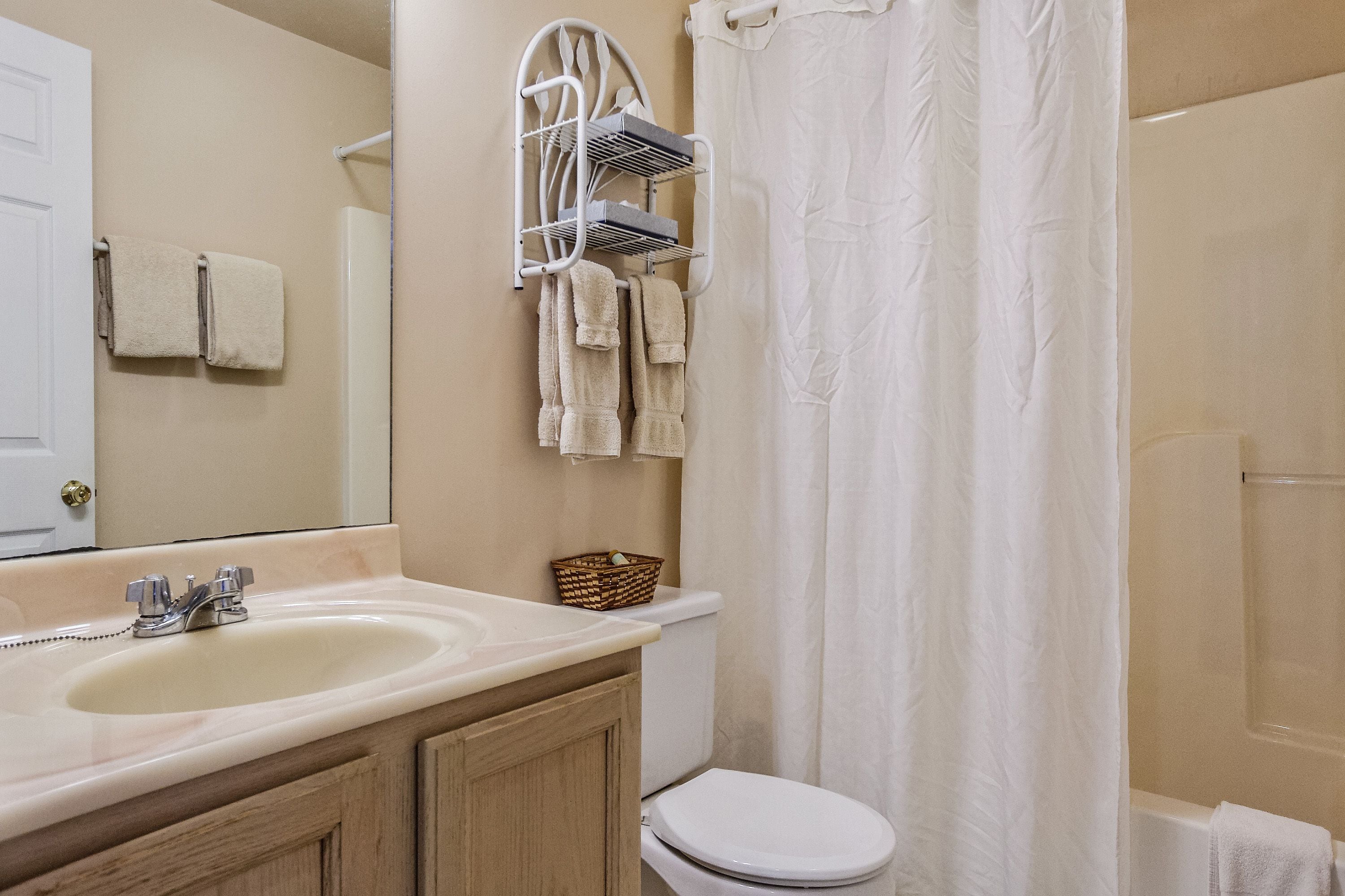 A bathroom with a sink, mirror, towel rack, and shower curtain.