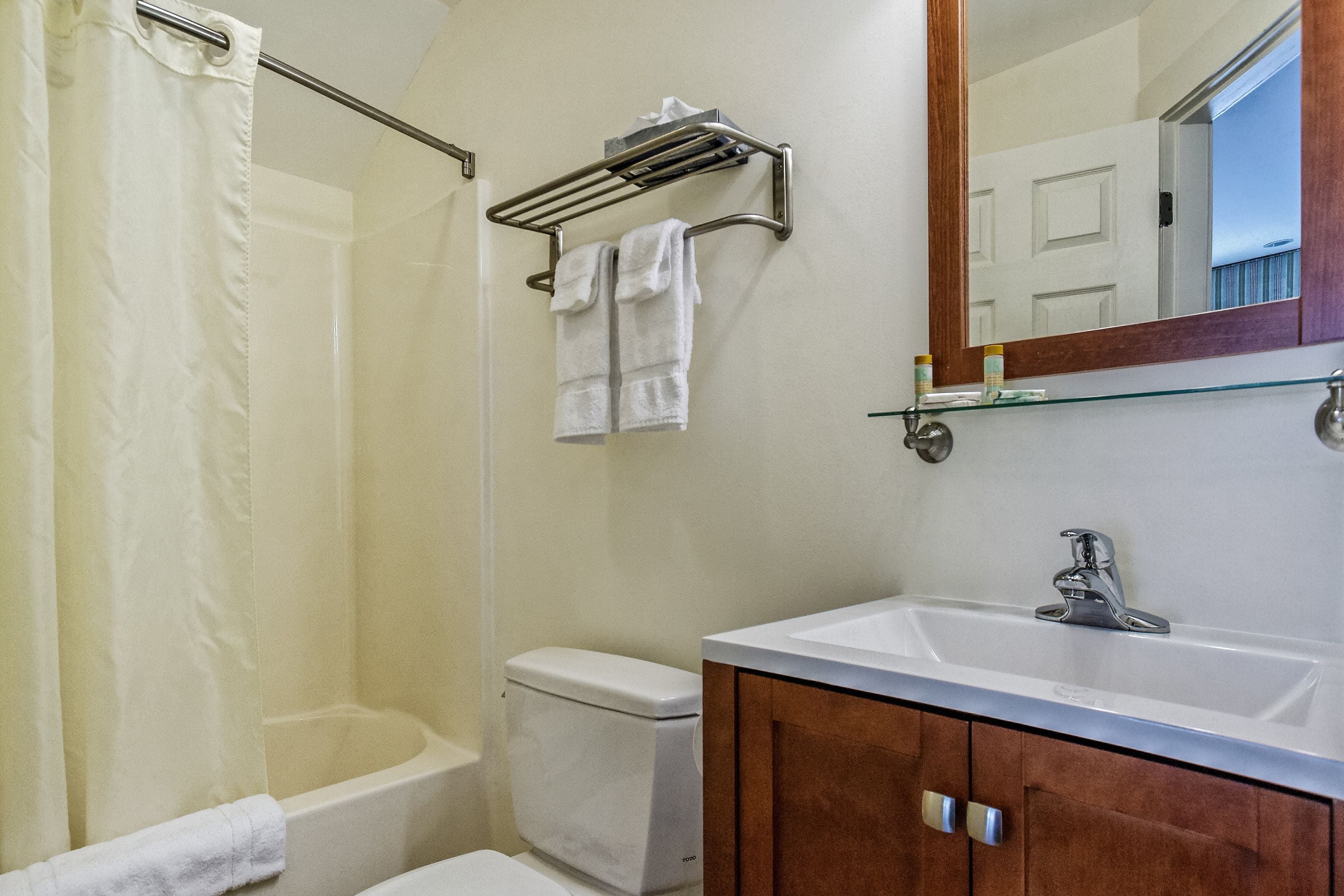 Un baño con ducha, inodoro, lavabo y espejo.