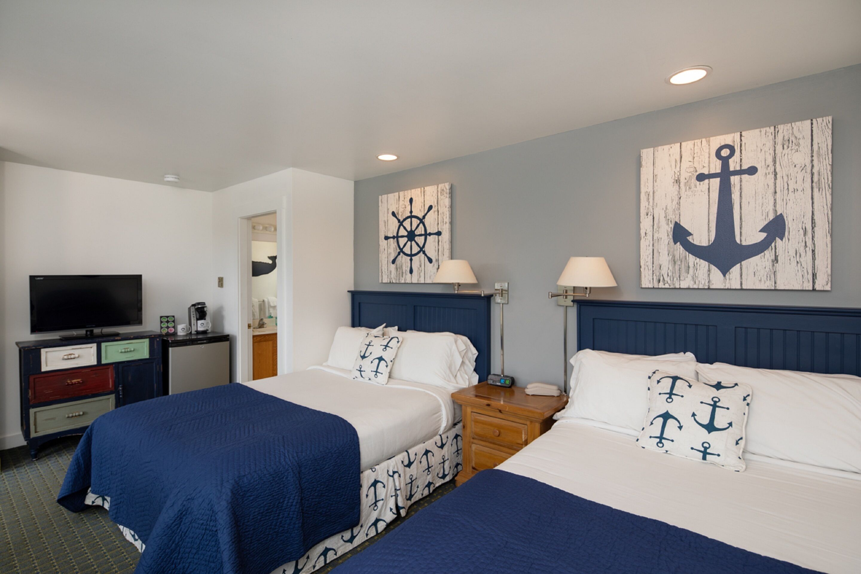 A hotel room with two beds, a TV, a desk, and a wardrobe.