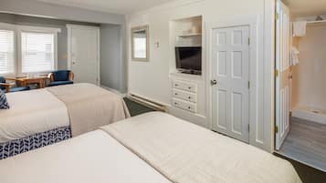 A hotel room with two beds, a TV, a desk, and a bathroom with a shower.