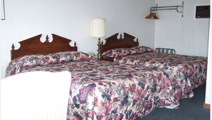 A double bed with floral bedding, a bedside table with a lamp, and a wall-mounted towel rack. - Eastview Motel (Saco)