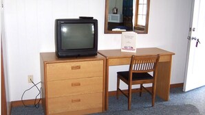 A room with a wooden desk, a television, a mirror, and a chair. - Eastview Motel (Saco)