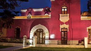 Un edificio con fachada roja, entrada en arco y ornamentación de hierro forjado.