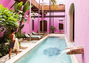 Zona de piscina con sillas de descanso y una persona de pie junto a la piscina.