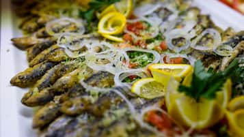 A platter of grilled fish garnished with lemon slices, onions, and herbs.