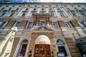 A hotel facade with a classic architectural style, featuring ornate details and a prominent entrance.