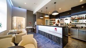 A hotel reception area with a marble counter, seating area, and a bar. - Hotel Continental (Rijeka)