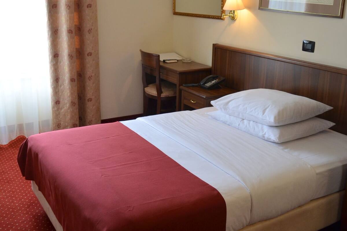 Una habitación de hotel con una cama, un escritorio, una silla y un teléfono.