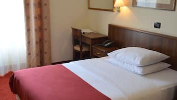 Une chambre d’hôtel équipée d’un lit, d’un bureau, d’une chaise et d’un téléphone.