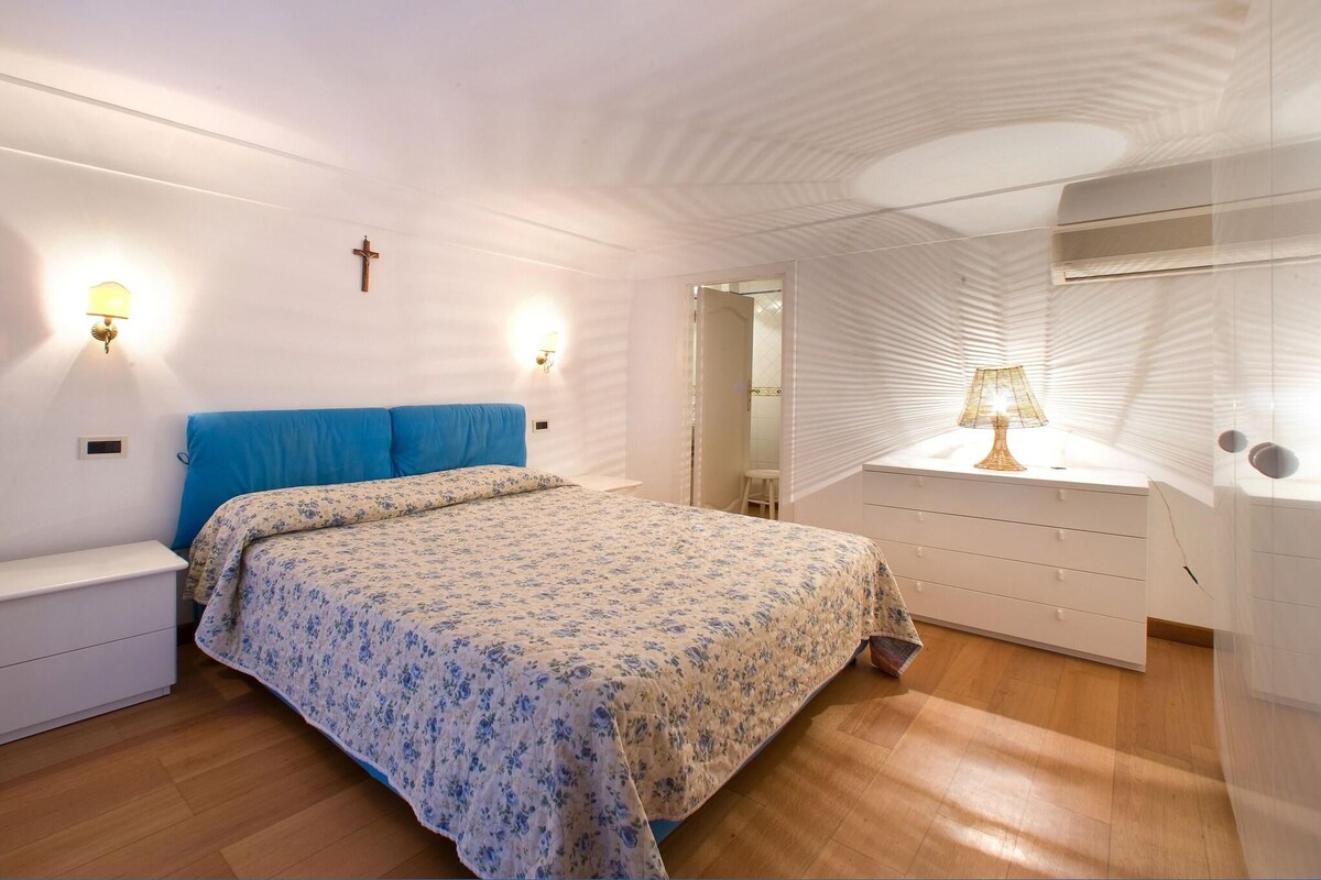 Une chambre à coucher avec un lit, des tables de chevet, une commode et un miroir.