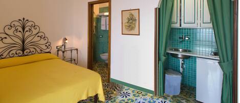 A bedroom with a bed, a small table, and a bathroom visible through an open door.